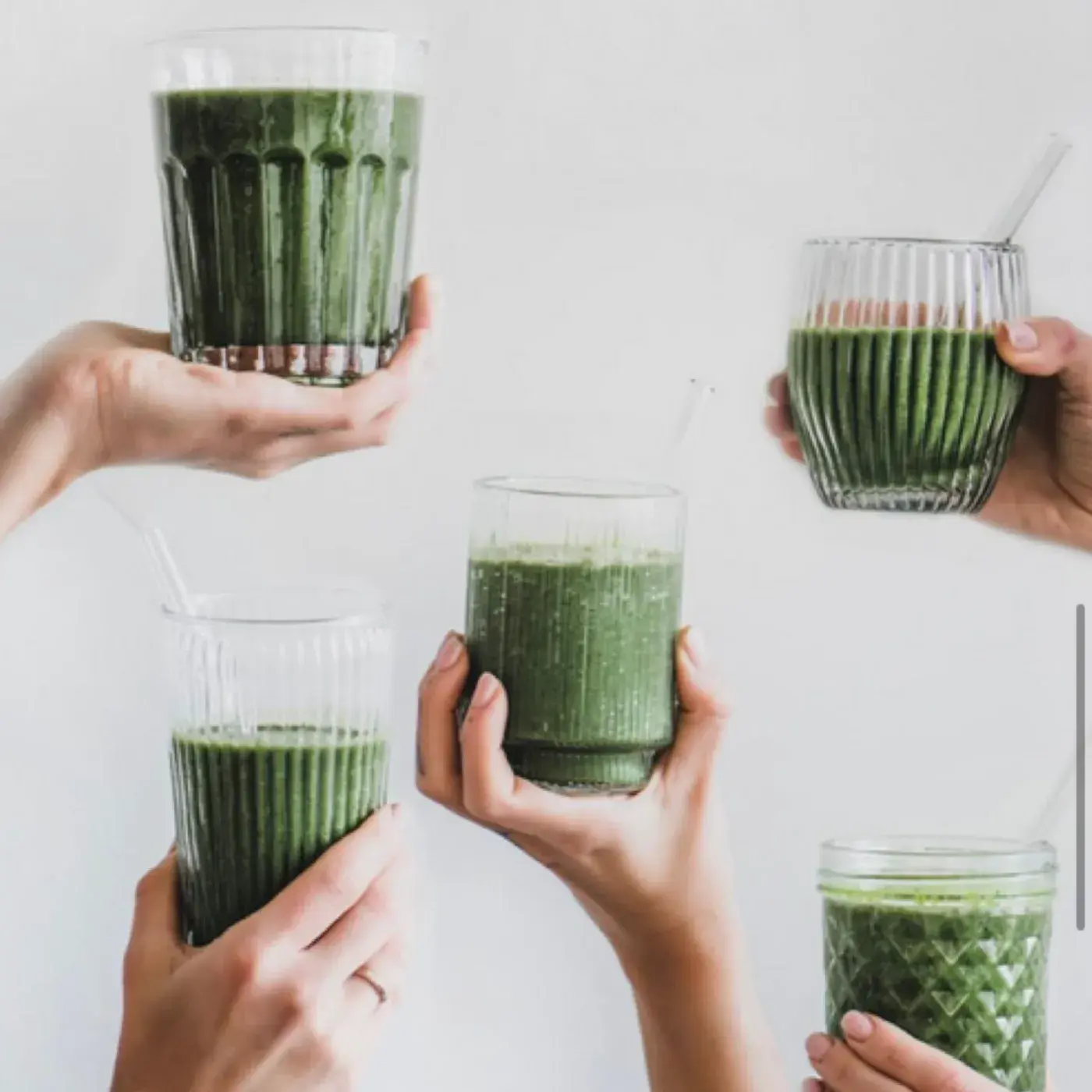 Neljä kättä kohottaa vihreitä smoothie-laseja